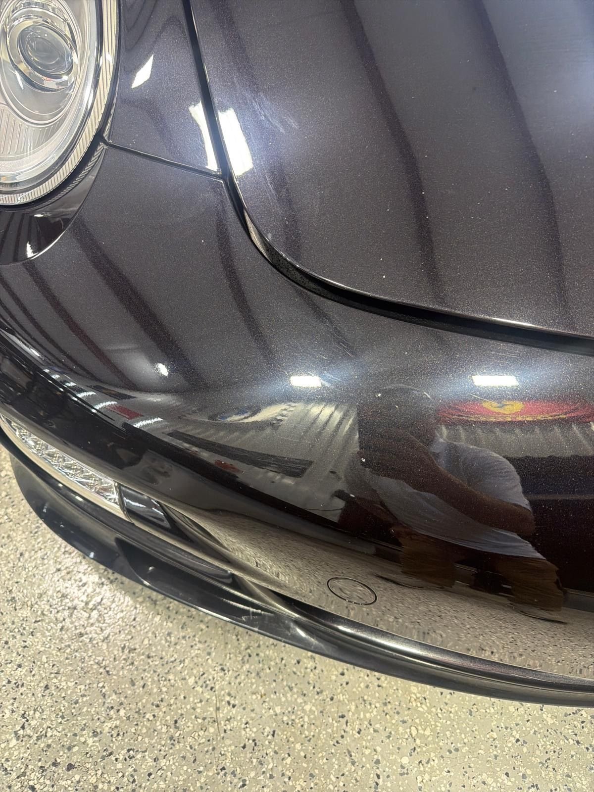 Polished Porsche 911 front fender reflecting shop lights